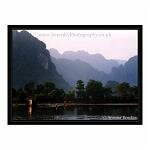 Stark mountains on the other side of the river, and a Landrover highlighted by the sun. Vang Vien, Laos